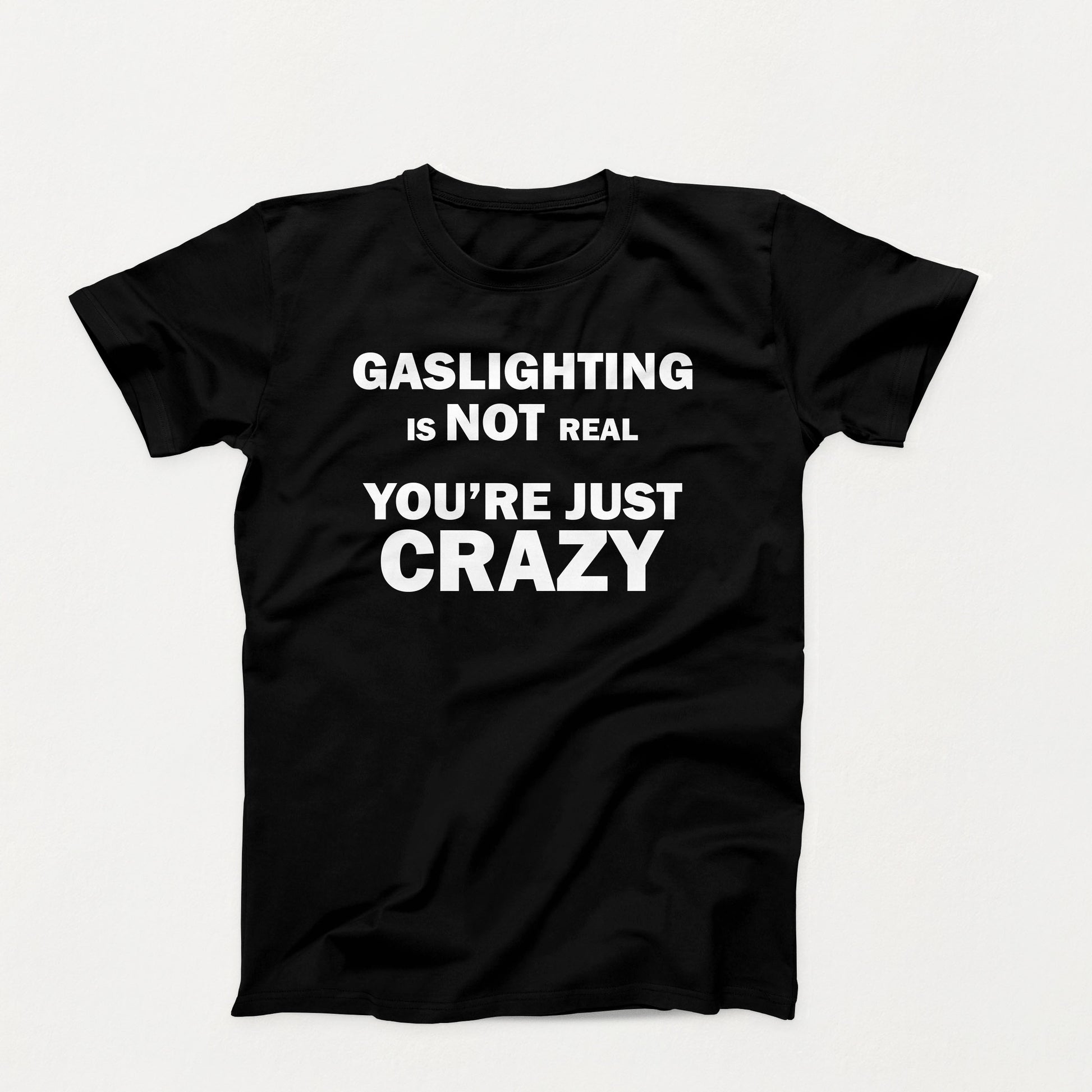 Black t-shirt with white bold text that reads “Gaslighting is not real — you’re just crazy,” designed for dark humor and sarcastic commentary
