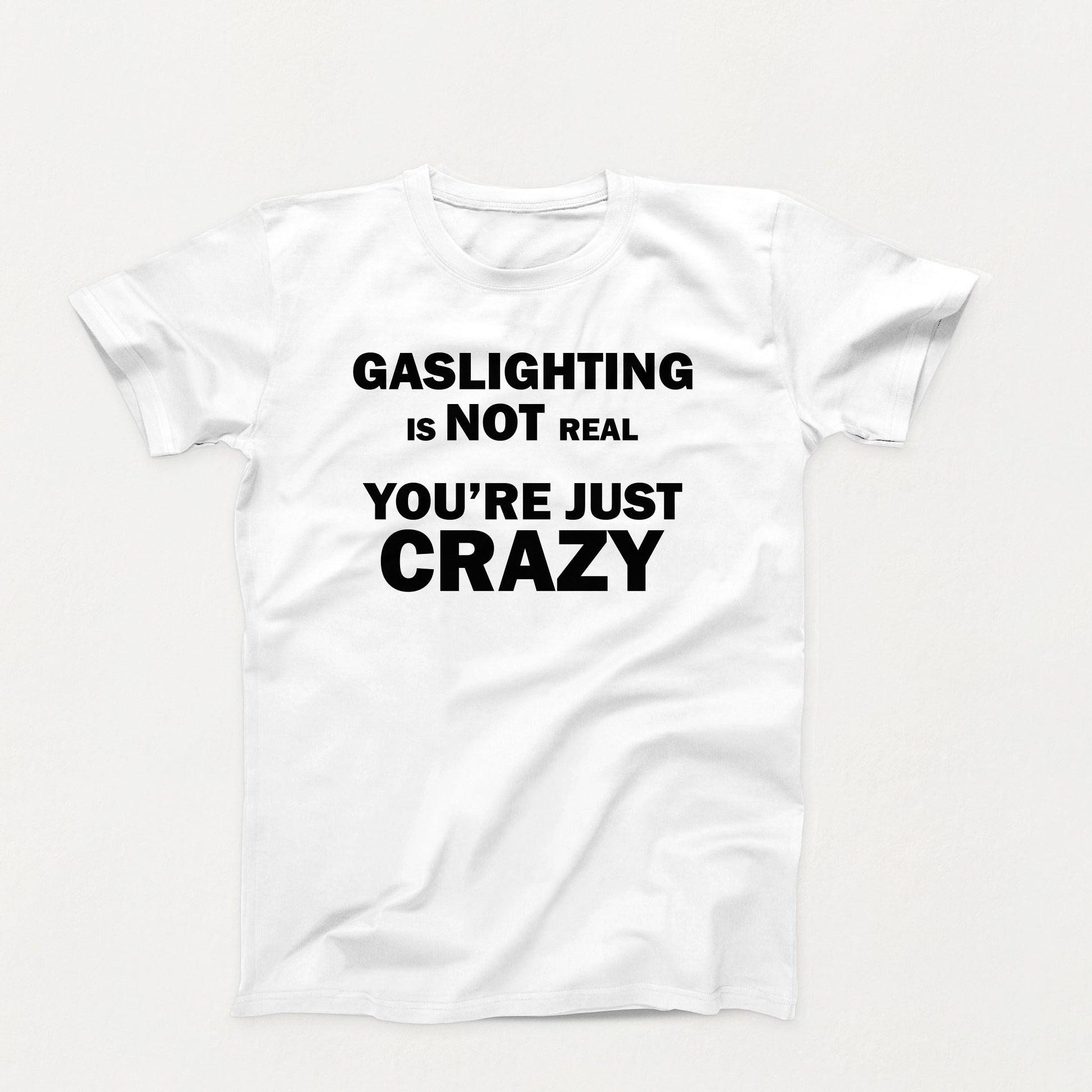 white t-shirt with black bold text that reads “Gaslighting is not real — you’re just crazy,” designed for dark humor and sarcastic commentary